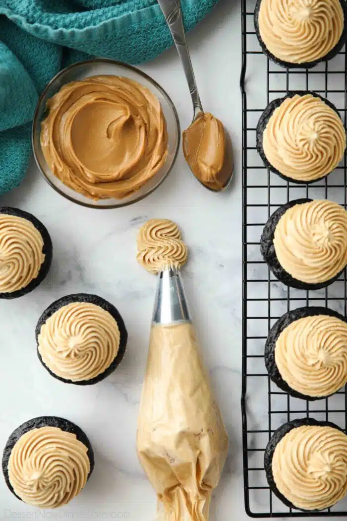 Piping bag of peanut butter frosting with an open star piping tip.