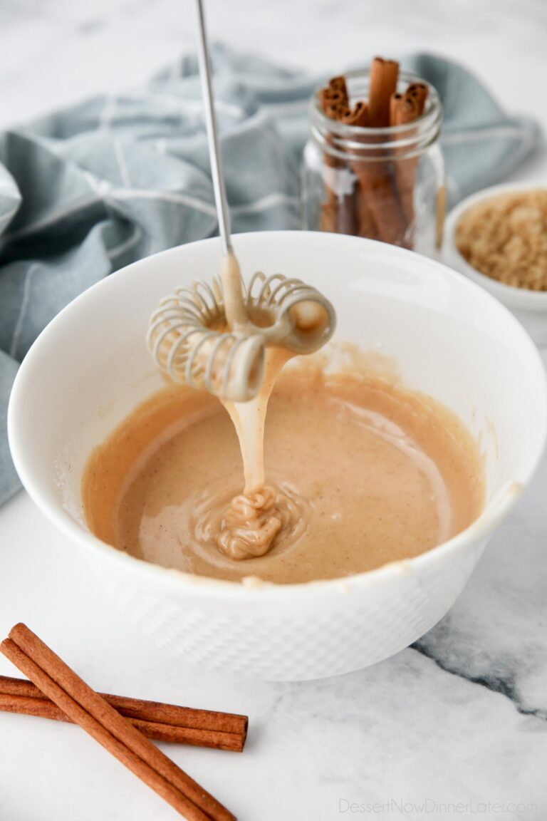 Cinnamon brown sugar glaze dripping off of a whisk into a bowl.