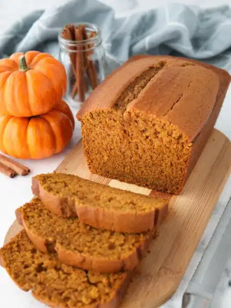 Loaf of pumpkin bread on a cutting board with some slices cut.