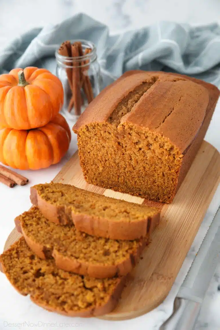 Loaf of pumpkin bread on a cutting board with some slices cut.