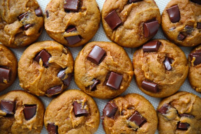 Closeup of pumpkin chocolate chunk cookies on a silicone baking mat.