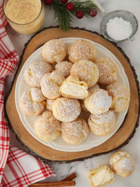 Top view of eggnog cream puffs with one cut open in the center.