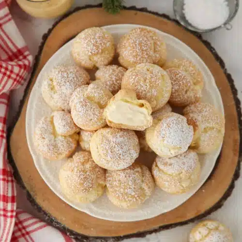 Top view of eggnog cream puffs with one cut open in the center.