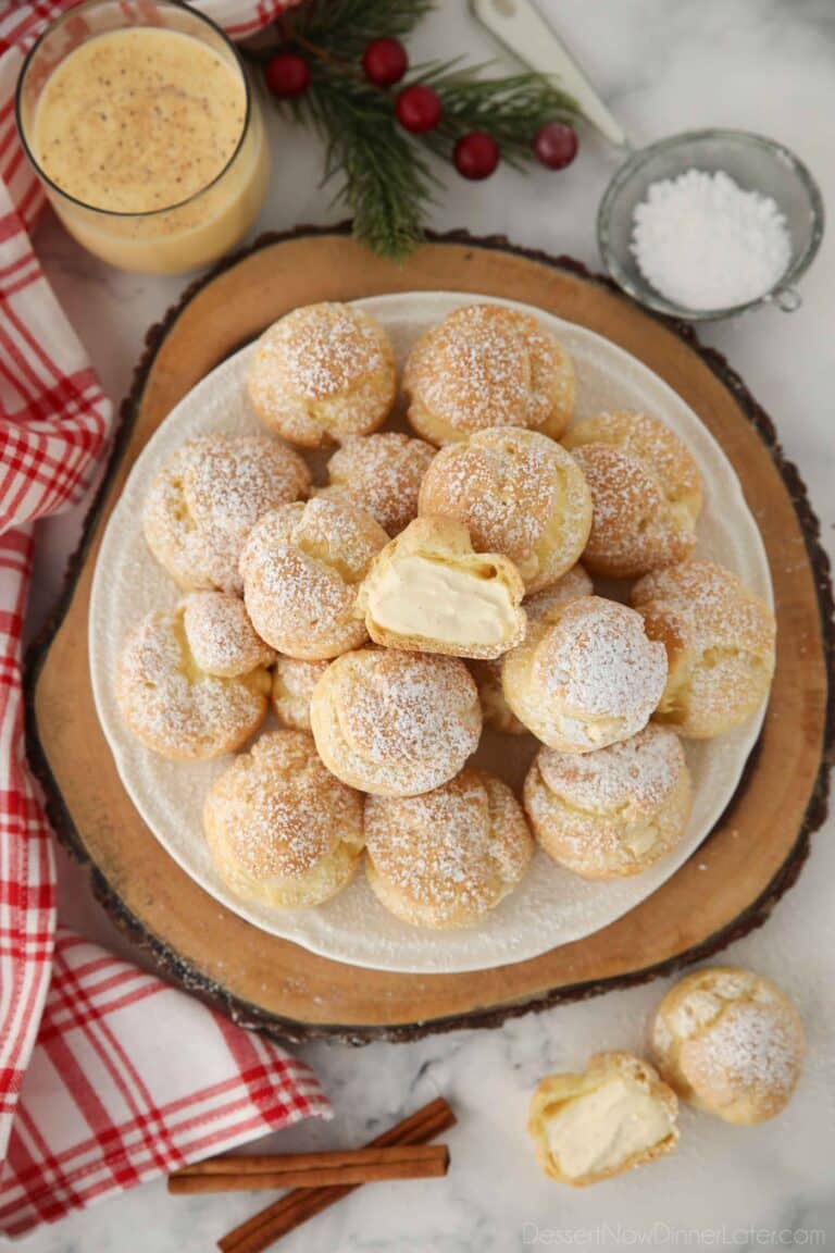 Top view of eggnog cream puffs with one cut open in the center.