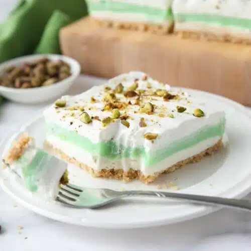 Layered pistachio dessert on a plate with a fork-full taken out.