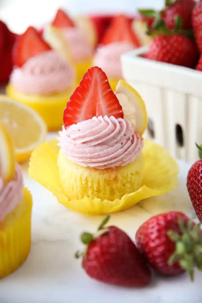 Wrapper pulled down from a lemonade cupcake topped with strawberry frosting.
