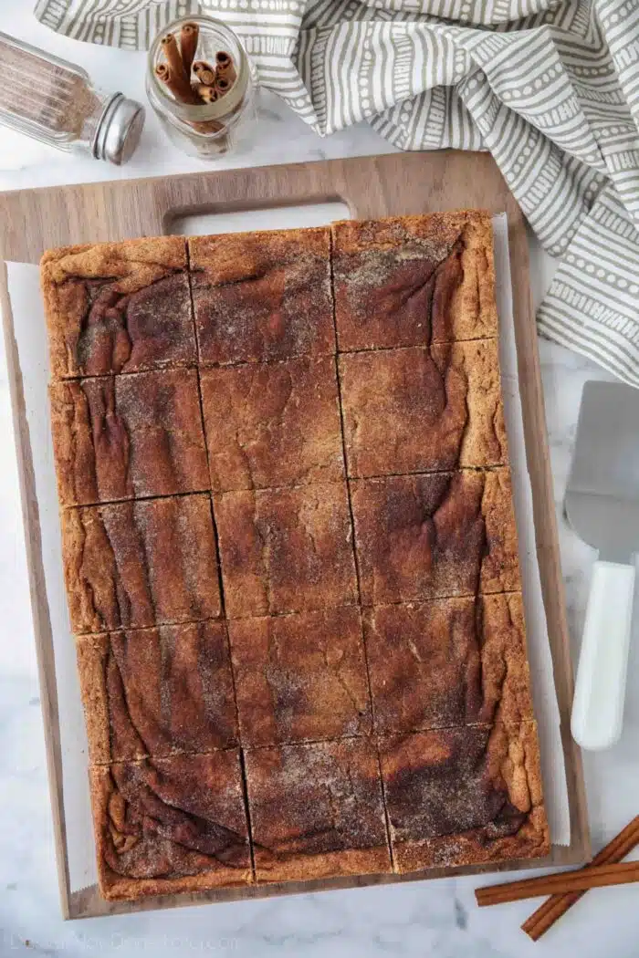 Cinnamon Bars cut into squares on a wooden cutting board.