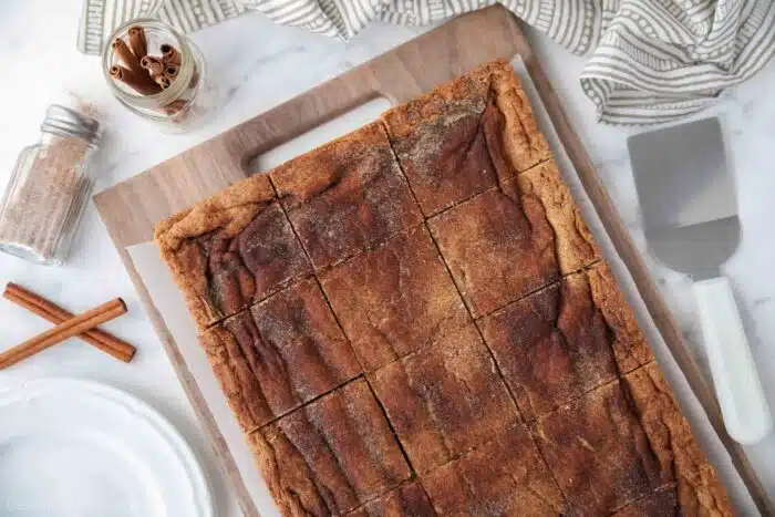 Cinnamon Bars cut into squares on a wooden cutting board.