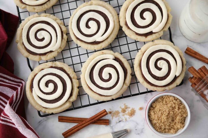 Top view of Cinnamon Roll Sugar Cookies with swirled frosting on a wire cooling rack.