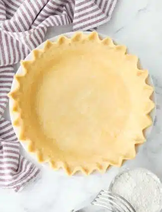 Top view of perfect pie crust in a pan with crimped edges.