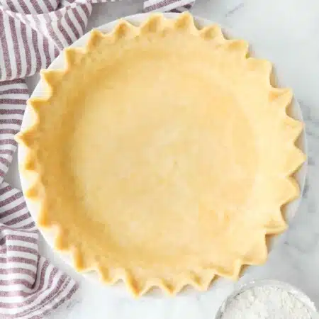 Top view of perfect pie crust in a pan with crimped edges.