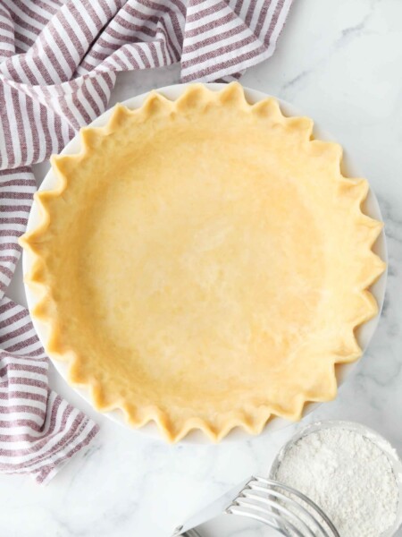 Top view of perfect pie crust in a pan with crimped edges.