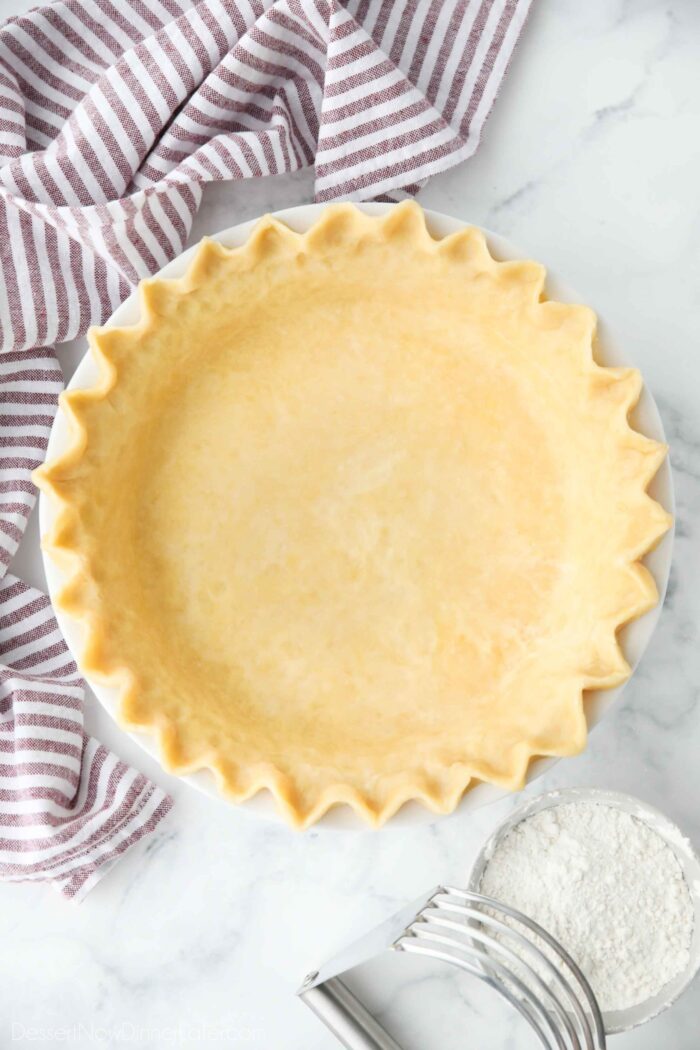 Top view of perfect pie crust in a pan with crimped edges.