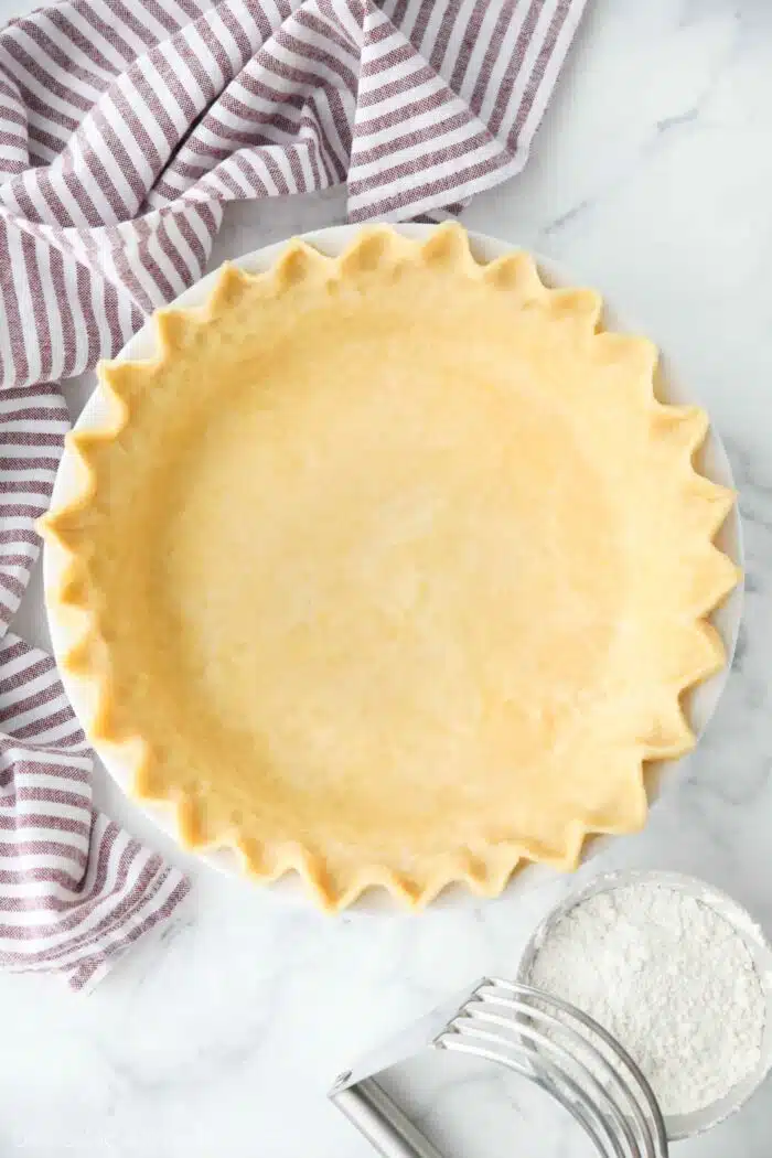 Top view of perfect pie crust in a pan with crimped edges.