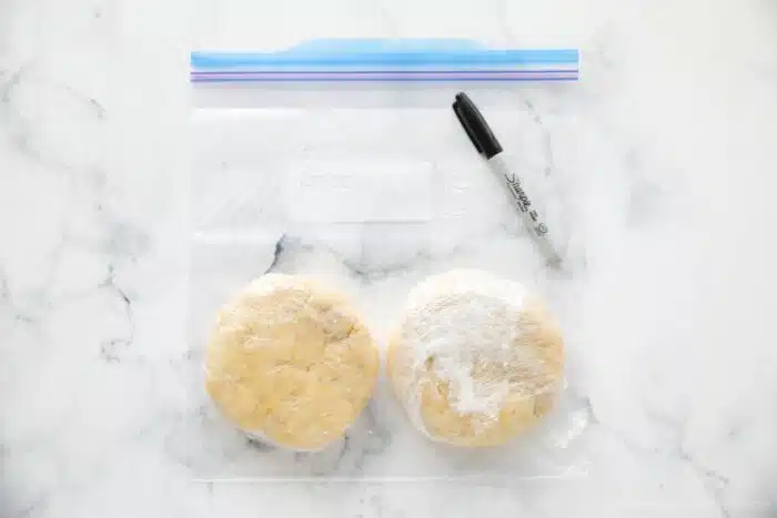 Wrapping pie crust disks with plastic wrap to chill or freeze.