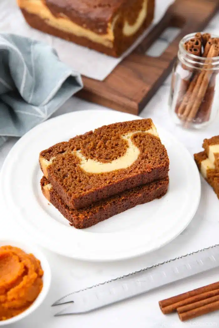 Slices of pumpkin cream cheese bread on a plate showing the marbled layers.