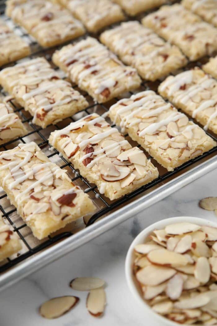 Glazed almond bars on a wire rack inside of a sheet pan.