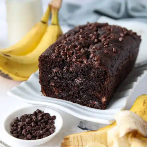 Chocolate banana bread with chocolate chips on a serving plate.