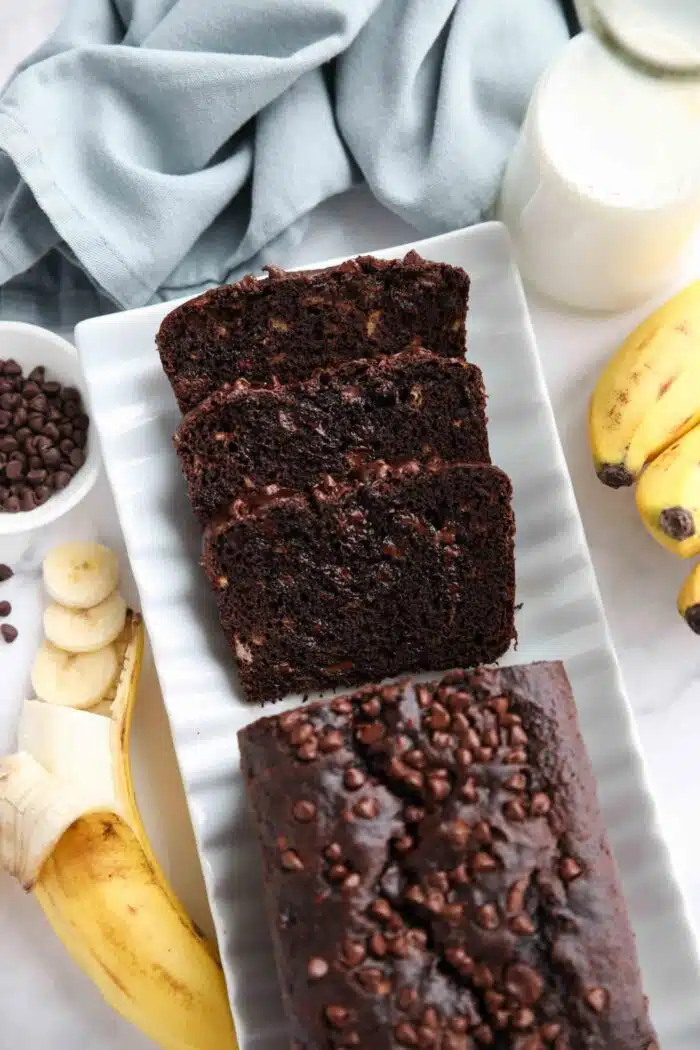 Top view of chocolate banana bread on a serving plate with a few slices cut off the end.