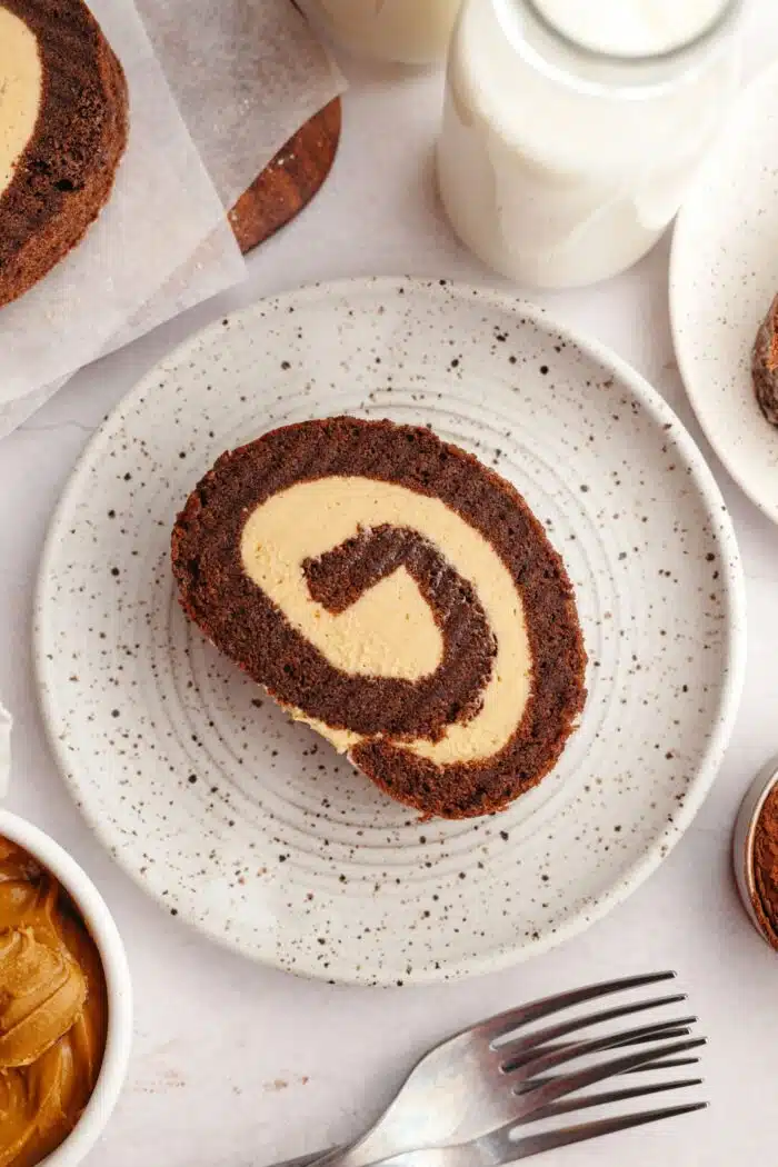 A slice of chocolate sponge roulade with peanut butter cake filling on a plate.