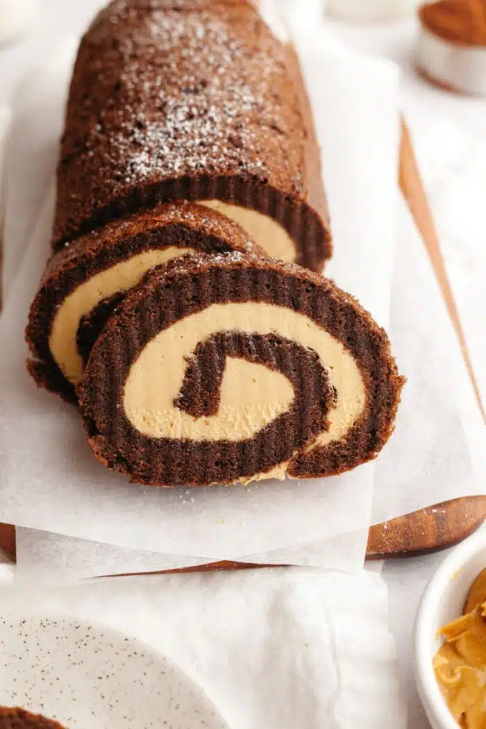 Slices cut off the end of a chocolate roulade with peanut butter cream cake filling.