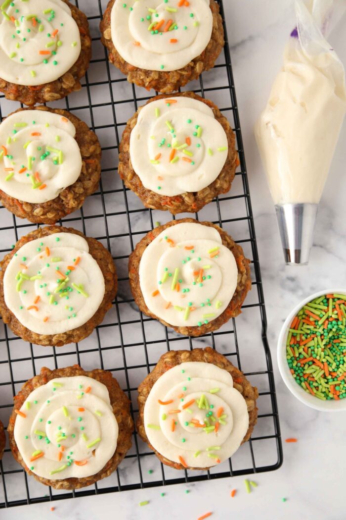 Carrot cake cookies with cream cheese frosting and sprinkles on top.