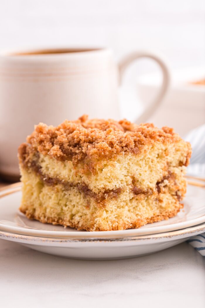 Slice of cinnamon coffee cake on a plate with a layer of cinnamon streusel in the middle and on top.