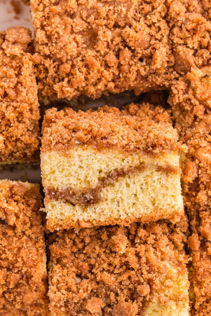 Cinnamon coffee cake in a pan with one slice on its side showing a layer of cinnamon streusel in the middle and on top.