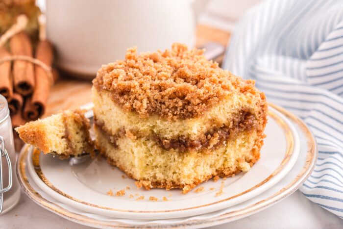 Cinnamon coffee cake on a plate with a forkful taken out.