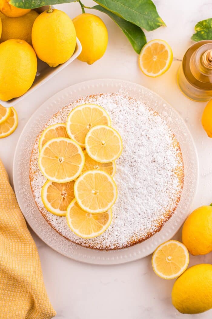 Top view of lemon olive oil cake with powdered sugar and lemon slices on top.