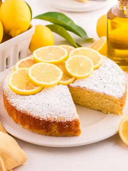 Lemon olive oil cake on a plate with a slice removed.