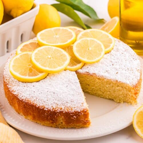 Lemon olive oil cake on a plate with a slice removed.