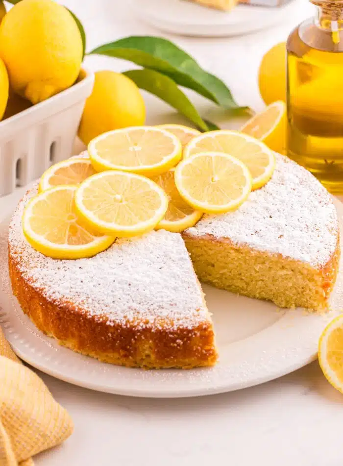 Lemon olive oil cake on a plate with a slice removed.