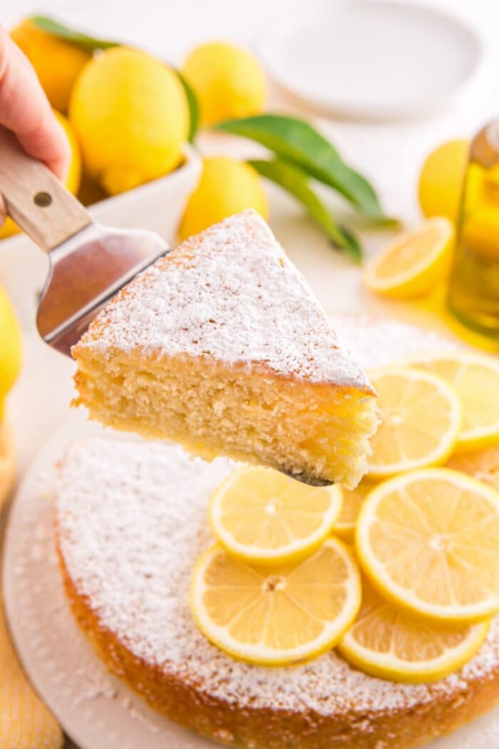 Slice of lemon olive oil cake being lifted up with a serving spatula.