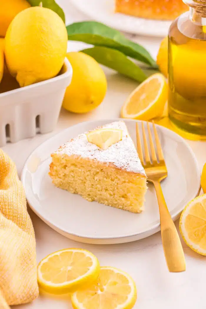 Slice of lemon olive oil cake on a plate with a fork.