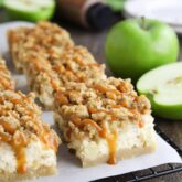 Caramel Apple Cheesecake Bars on a parchment lined wire cooling rack with caramel dripping down the sides.